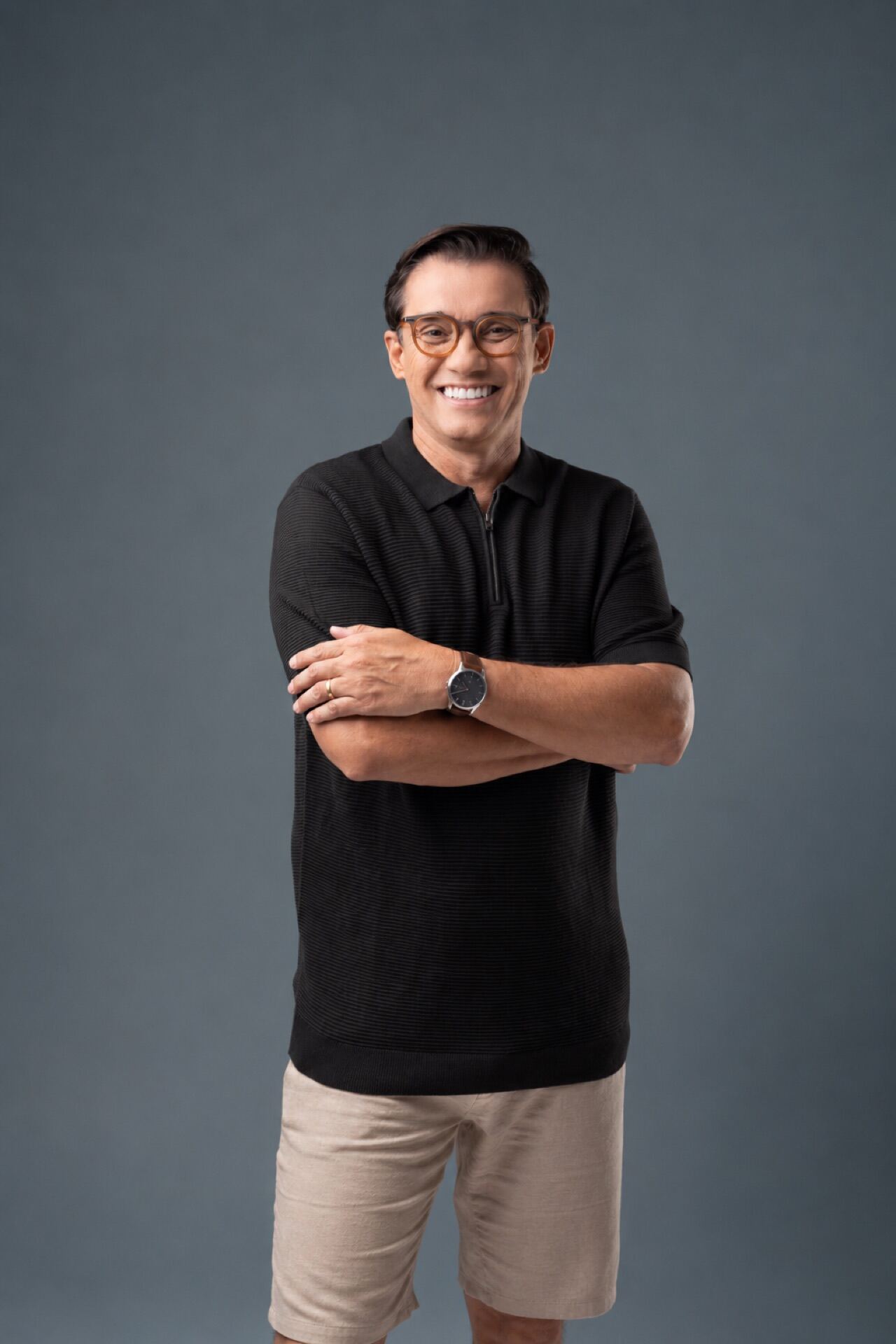 Marcos Paiva sorrindo de braços cruzados em foto profissional